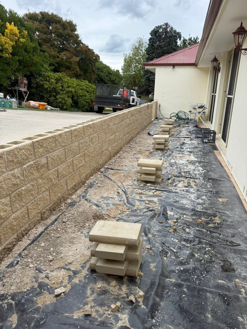 Sandstone-coloured block garden wall along the side of a house