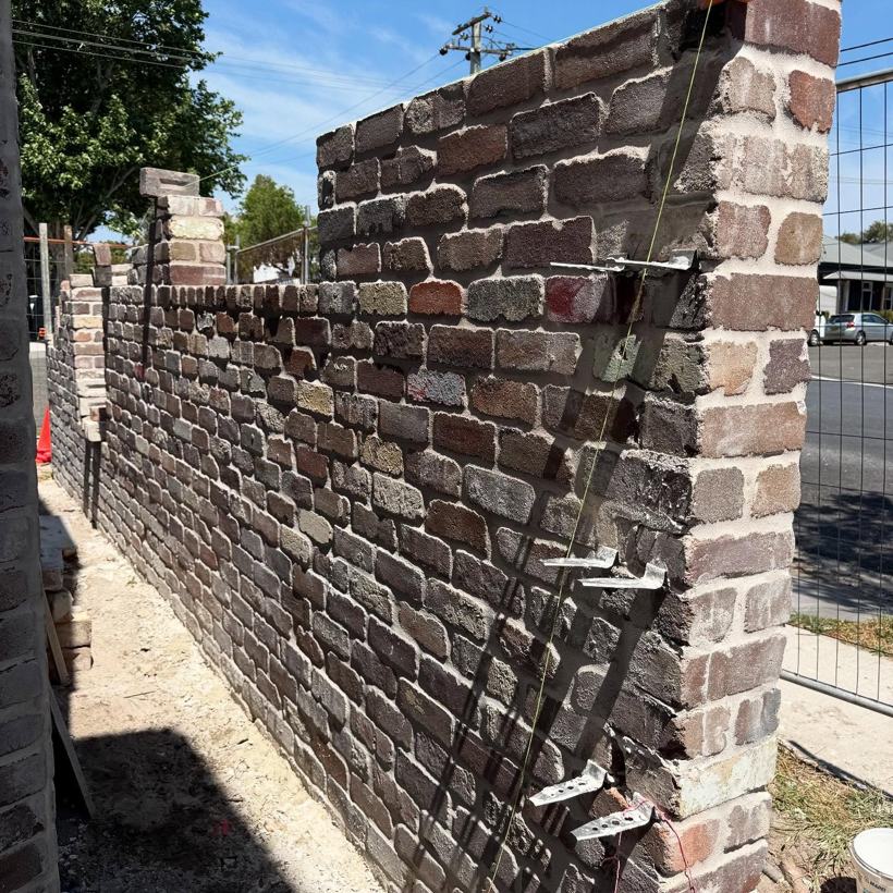 Long recycled-brick boundary wall with a pier