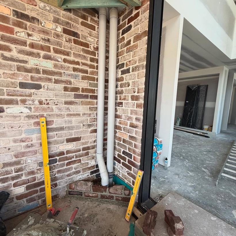 Brick panel beside a downpipe with a spirit level