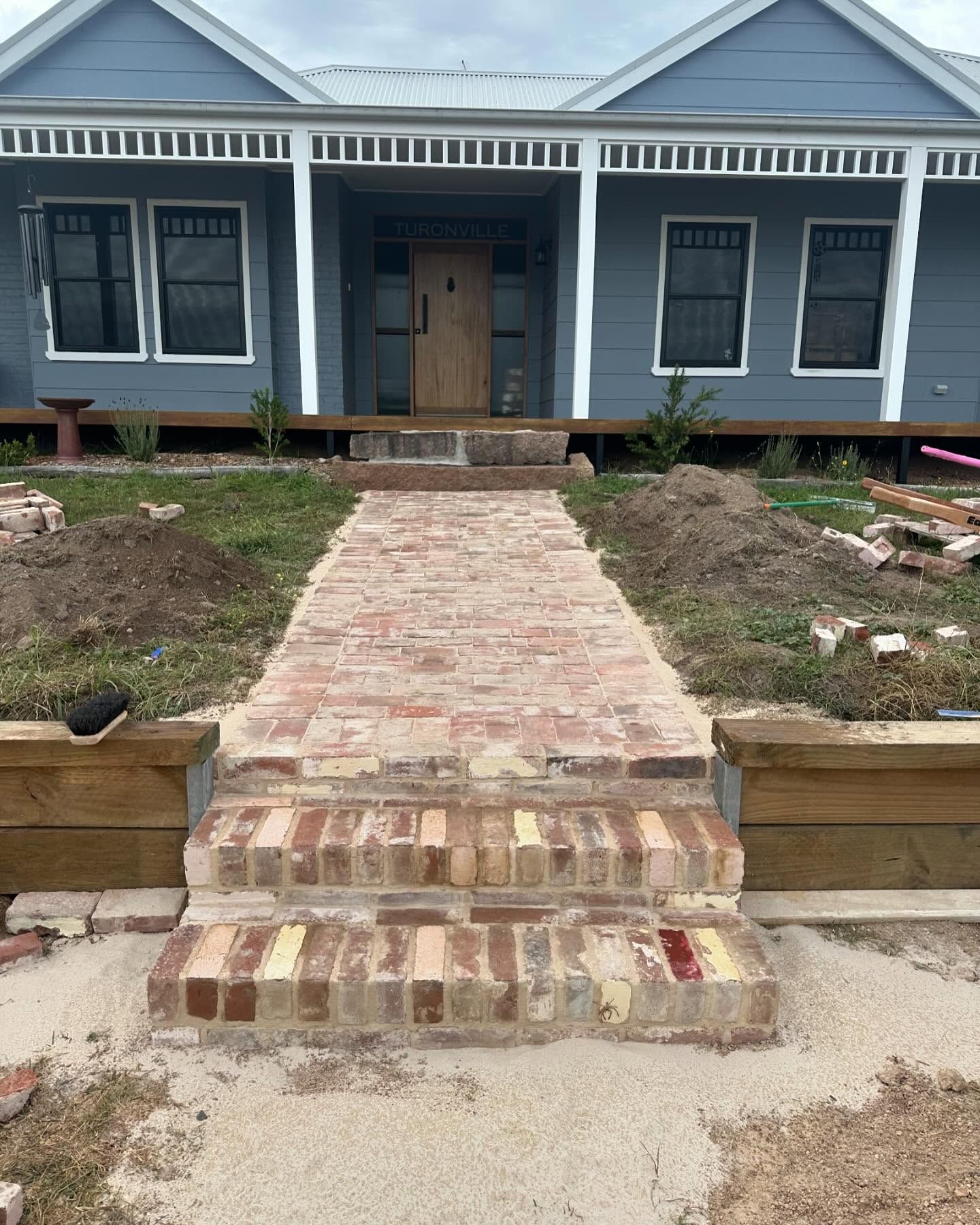 New recycled-brick front steps and path leading to a cottage verandah